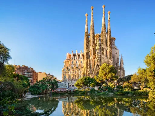La Sagrada Familia, simbolo di **attività Barcellona**, si specchia in un laghetto circondato da verde.