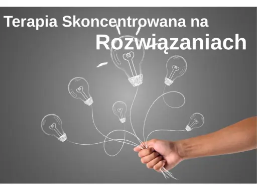 Dłoń trzymająca pęk żarówek narysowanych kredą na szarym tle.