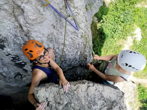Dwie osoby w kaskach wspinają się po skale na Jurze Krakowsko-Częstochowskiej.
