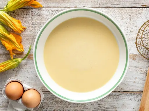 Pastella per fiori di zucca pronta in ciotola, con fiori freschi e uova a lato.