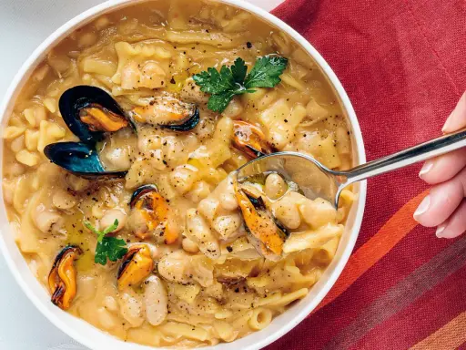 Un plato humeante de pasta fagioli e cozze, con mejillones jugosos y alubias cremosas en un caldo sabroso.