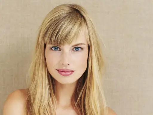 Blonde Frau mit blauen Augen und Pony. Eine Anleitung zum Pony schneiden könnte hier nützlich sein, um diesen Look zu erzielen.
