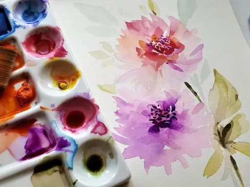 Paleta de acuarelas con pincel y flores en proceso. Inspiración para pintar con acuarelas.