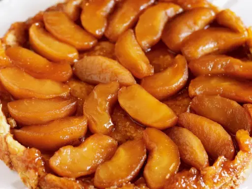 En gyllene tarte tatin med karamelliserade äppelklyftor som glänser. En klassisk fransk dessert som smälter i munnen.