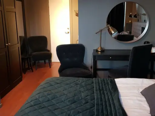Ett modernt rum på Haparanda Stadshotell med en stor säng, skrivbord, spegel och bekväma fåtöljer.