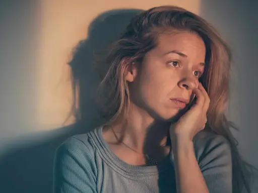 Une femme songeuse, le regard perdu, se demande : "suis je sous l'emprise d'un manipulateur test ?" Son visage exprime le doute et l'inquiétude.