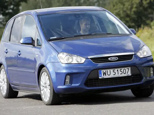 Niebieski Ford C-Max 1.6 TDCI z mężczyzną za kierownicą jedzie po drodze wśród zieleni.