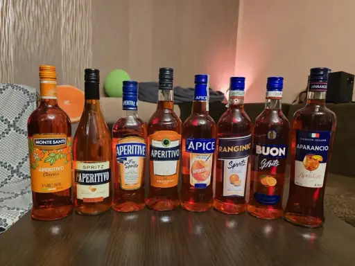 Rząd butelek z pomarańczowym, lekkim alkoholem, idealnym na letnie wieczory. Wśród nich Monte Santi, Aperitivo, Apice, Ranginino, Buon Spritz i Aparancio.