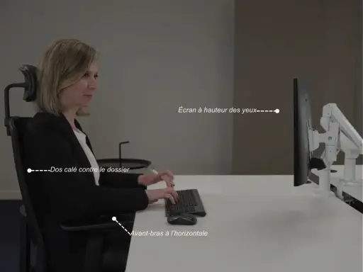 Une femme assise, respectant la règle ergonomique : dos calé, avant-bras à l'horizontale, écran à hauteur des yeux.