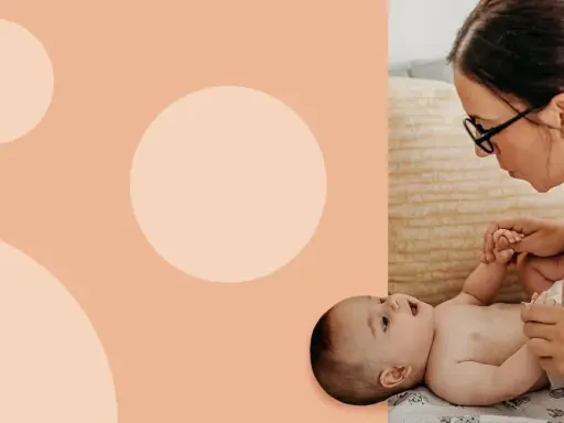 Mama z okularami delikatnie podnosi nóżki dziecka, przygotowując się do zakładania pampersa na stojąco.