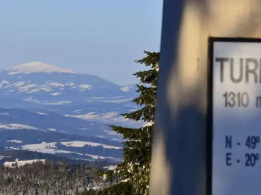 Zimowy krajobraz z Turbacza, szczytu o wysokości 1310 m n.p.m. Śnieg pokrywa okoliczne góry i lasy.