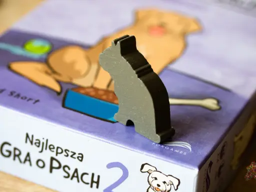 Szary kotek na pudełku gry planszowej "Najlepsza gra o psach". Czas na wspólną grę z pieskami!