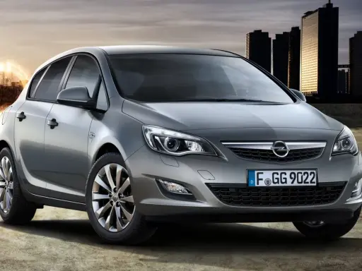 Szary Opel Astra 1.4 Turbo z nowoczesnymi światłami i felgami, na tle miejskiej panoramy i energetycznego kręgu.