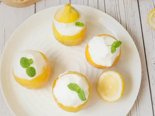 Délicieux citron givré, des citrons évidés remplis de sorbet et décorés de menthe fraîche. Un dessert rafraîchissant et visuellement attrayant.