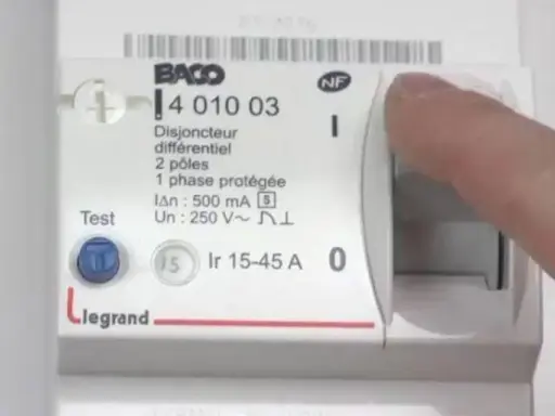 Main d'une personne actionnant le levier d'un disjoncteur différentiel Legrand, modèle 15-45 A.