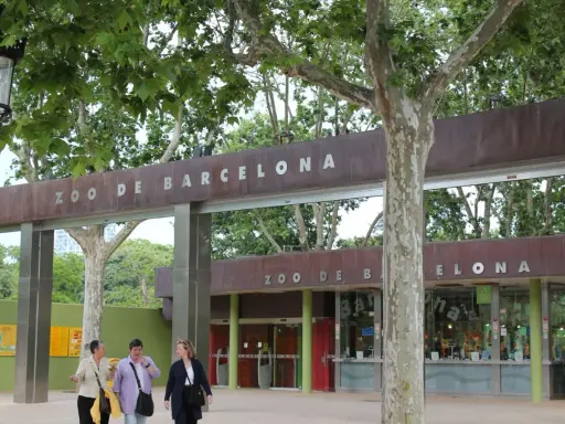Eingang zum Zoo de Barcelona mit drei Frauen, die davor spazieren gehen.