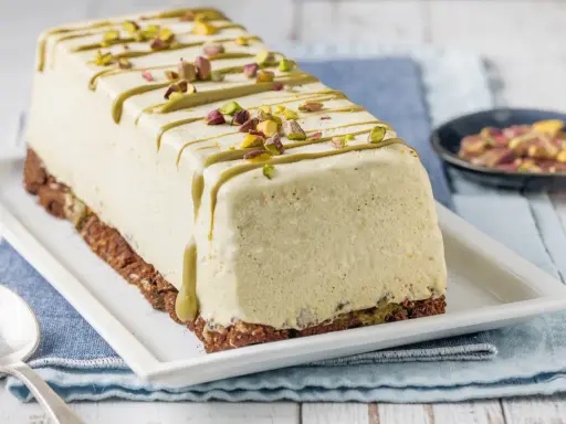 Semifreddo al pistacchio decorato con glassa verde e granella di pistacchi, su base croccante.