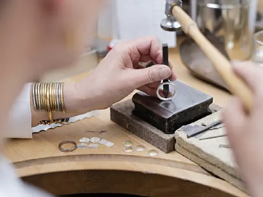 Un orfèvre au travail, façonnant une bague avec précision. Son métier d'orfèvre demande patience et dextérité.
