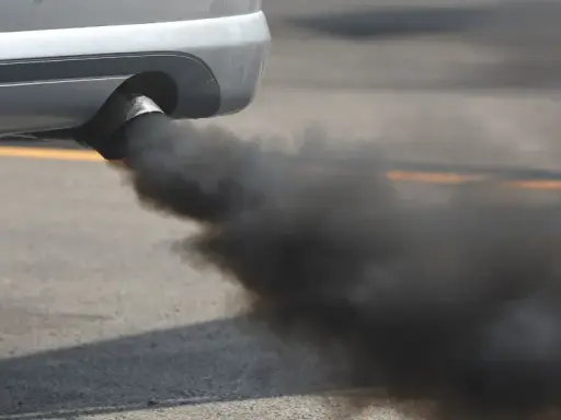 El tubo de escape de un coche emite una densa nube de humo negro al acelerar, contaminando el aire.