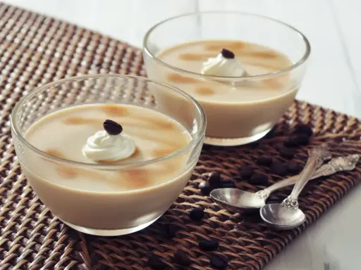 Deux verrines de crème au café façon Danette, garnies de chantilly et d'un grain de café.