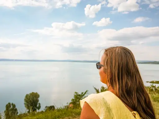 Kobieta w żółtej bluzce podziwia rozległy krajobraz nad Balatonem. To idealne miejsce na odkrywanie atrakcji i relaks.