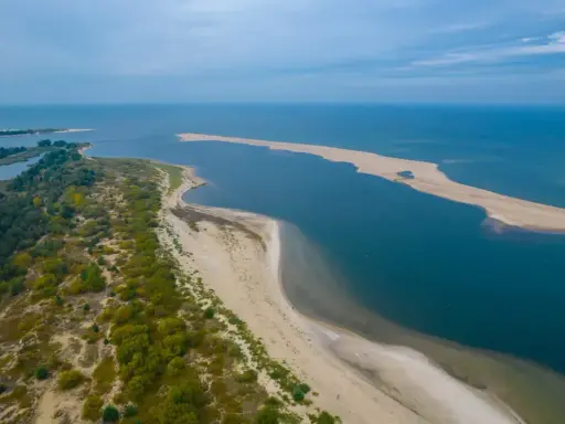 Piękny **urlop w Polsce** nad morzem. Piaszczysta plaża, zieleń i błękit wody tworzą malowniczy krajobraz.