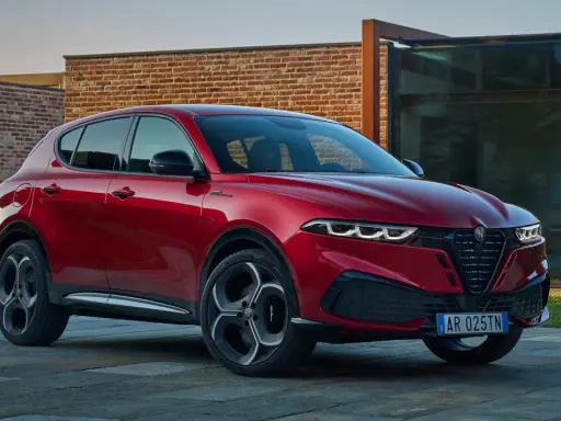Czerwone Alfa Romeo Tonale na tle nowoczesnej architektury. Sprawdź aktualną alfa romeo tonale cena i konfigurację.