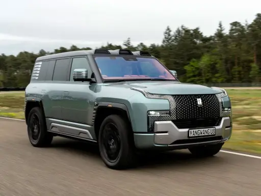 Ein mintgrüner Yangwang U8 fährt auf einer Straße, umgeben von Bäumen und Gras.