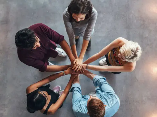 Un gruppo di persone unisce le mani, un'immagine che incarna la social definizione di unità e collaborazione.