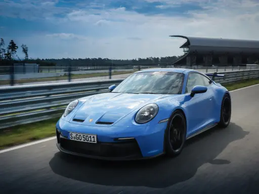 Ein blauer Porsche GT3 Rennwagen rast auf einer Rennstrecke.