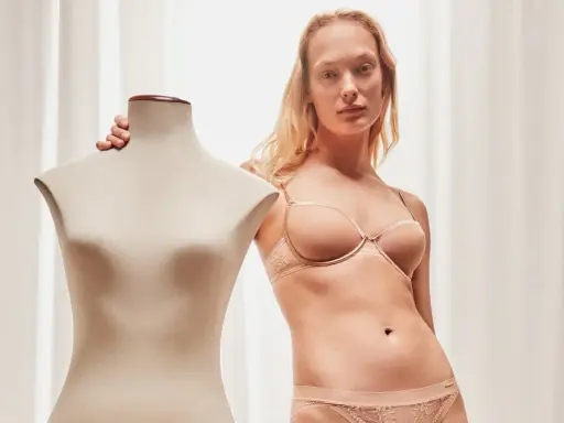 Modella con lingerie color carne, taglia italiana 85D, accanto a un manichino.
