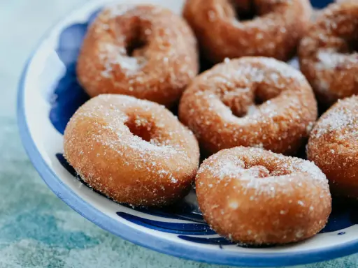 Rosquillas caseras de toda la vida, doradas y espolvoreadas con azúcar, listas para disfrutar.