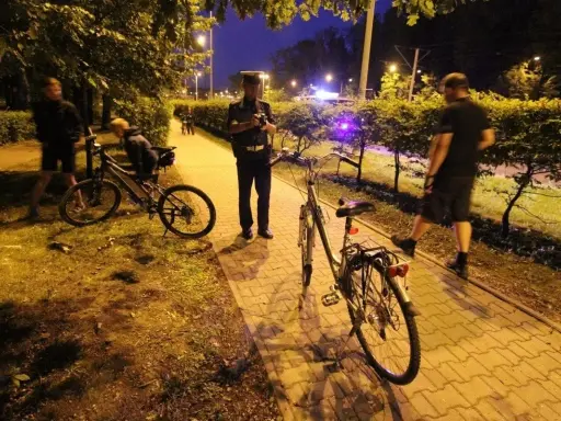 Policjant rozmawia z rowerzystą, który może stracić prawo jazdy. Nocna interwencja na ścieżce rowerowej.