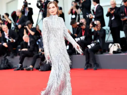 Isabelle Huppert, éblouissante dans sa robe argentée à franges, foule le tapis rouge de la mostra de Venise, sous le regard des photographes.