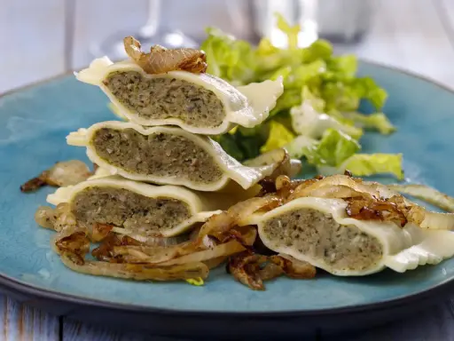 Gestapelte Maultaschen mit gebratenen Zwiebeln und Salat. Ein köstliches Maultaschen Rezept, das Appetit macht.
