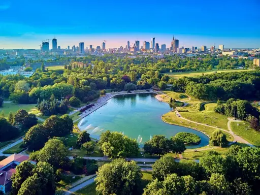 Piękny park z jeziorem i fontannami, idealne miejsce na relaks. W tle widać panoramę Warszawy, co czyni to jedno z fajnych miejsc w Warszawie.
