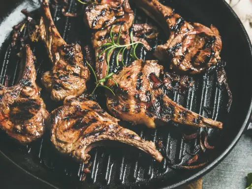 Saftige Lammkoteletts mit Grillstreifen in einer Pfanne, garniert mit Rosmarin. Perfekt zum Lamm grillen!