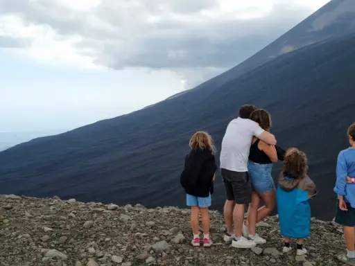 Famiglia in vacanza in Sicilia con bambini, ammira il pendio scuro di un vulcano.