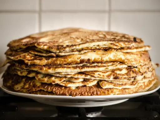 Pile généreuse de crêpes à la farine de châtaigne, dorées et appétissantes, prêtes à être dégustées.