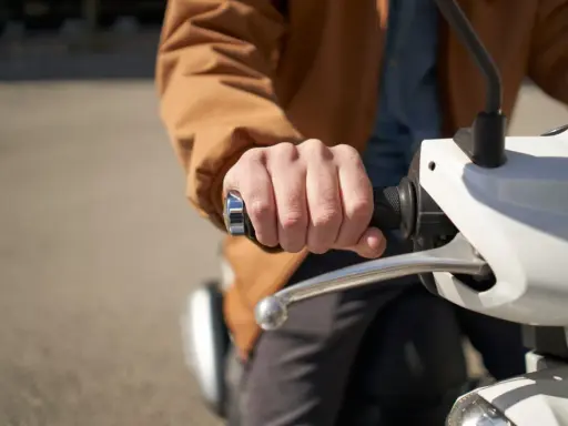 Dłoń trzymająca kierownicę skutera elektrycznego. Może to być związane z dopłatą do skutera elektrycznego.