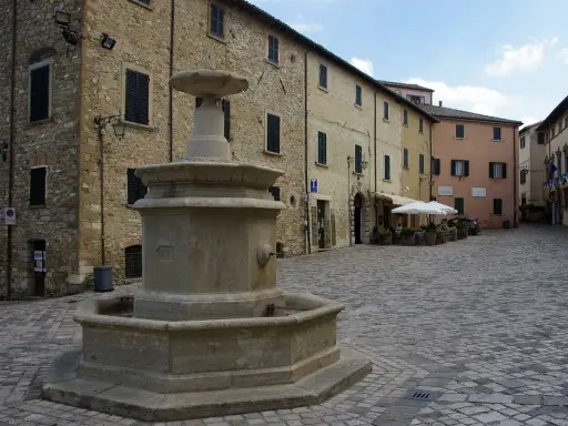 Piazza con fontana in pietra, circondata da edifici storici. Un angolo di pace nei borghi vicino Cattolica.