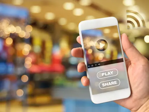 Dłoń trzyma smartfon Huawei, na ekranie którego widać interfejs odtwarzacza wideo z przyciskiem "PLAY" i "SHARE", sugerujący dostęp do treści z Google Play.
