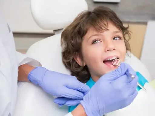 Chłopiec u dentysty, ciekawy, ile zębów ma roczne dziecko. Lekarz bada jego uśmiech.
