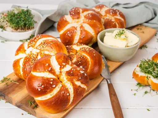 Frisch gebackene laugen knoten mit Sesam und grobem Salz, dazu Butter und Kresse.