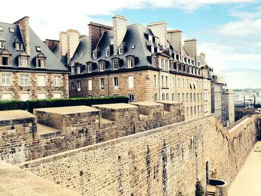 Murs de pierre de la ville fortifiée de Saint-Malo, avec des maisons bretonnes typiques et une vue sur la mer. Imaginez une pause à la taverne de Saint-Malo.