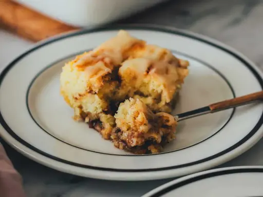 Ein Stück saftiger Zimtschneckenkuchen mit Zuckerguss, perfekt für ein Zimtschneckenkuchen Rezept.