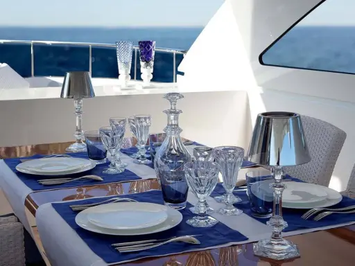 Emplacement des couverts sur une table dressée sur un yacht, avec des verres en cristal, une carafe et des lampes.