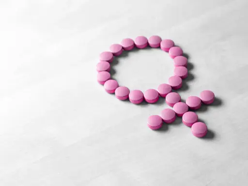 Rosa piller formar kvinnosymbolen. Kan symbolisera hormonbehandling, eller att urin luktar illa klimakteriet.