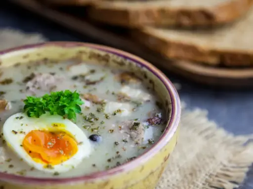 Żur z jajkiem i majerankiem, idealne jakie przyprawy do żuru. Obok kromki chleba.