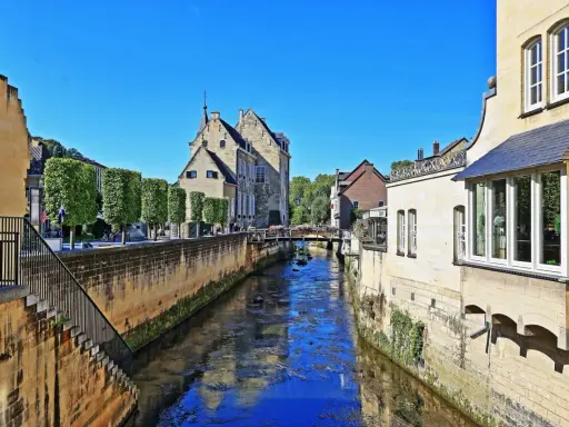 Idyllischer Kanal in der Valkenburg Altstadt, gesäumt von historischen Gebäuden und Bäumen.
